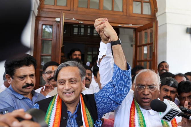 Mallikarjun Kharge, newly elected president of India's main opposition Congress party, raises his hand with party colleague Shashi Tharoor at Kharge’s residence in New Delhi
