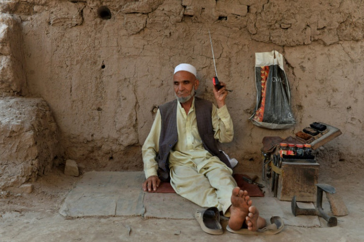 A shoeshiner listens to the radio in 2020 on the outskirts of Jalalabad, Afghanistan