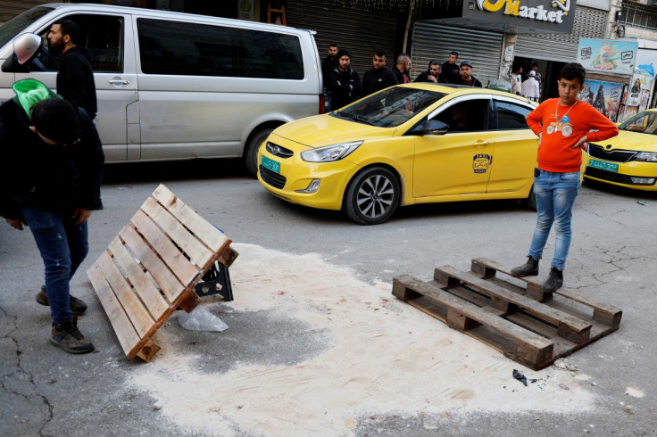 People gather as sand is seen covering the site where Palestinians were killed in Jenin