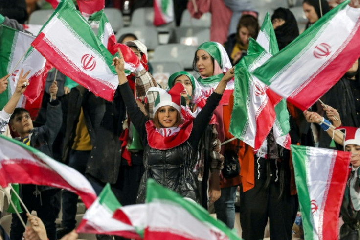 Women football fans wave Iranian flags during the friendly match between Iran and Russia at Azadi Stadium in Tehran