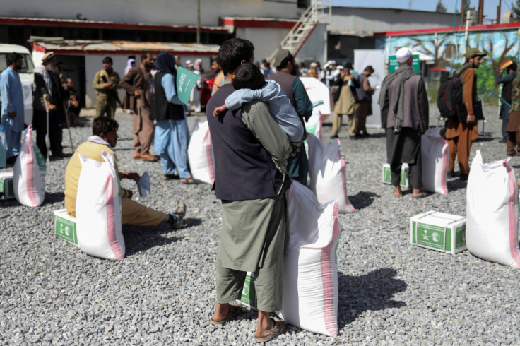 Afghan man with his son wait to receive a food package distributed in Kabul