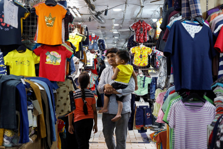 A family shops for children's dresses at a market, ahead of Eid al-Fitr celebrations in Karach
