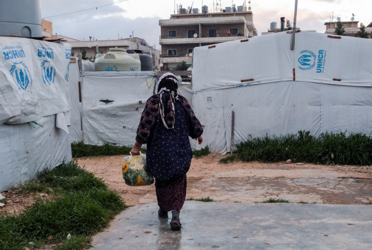 A Syrian refugee walks near tents at an informal settlement, in Al-Marj