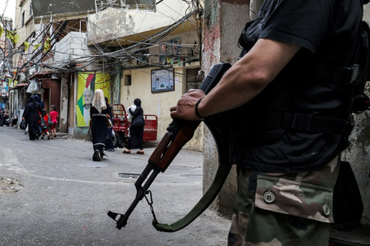 A fighter stands with an assault rifle in an alley of the Shatila camp for Palestinian refugees in the southern suburbs of Beirut