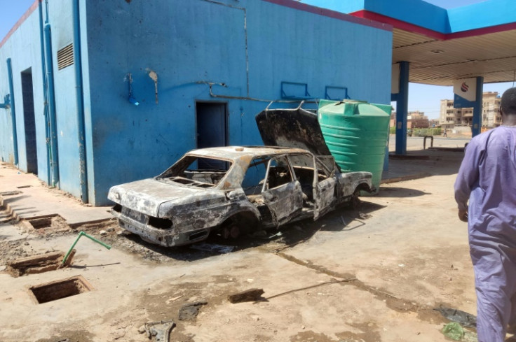 A man walks toward a charred car at a looted petrol station in southern Khartoum