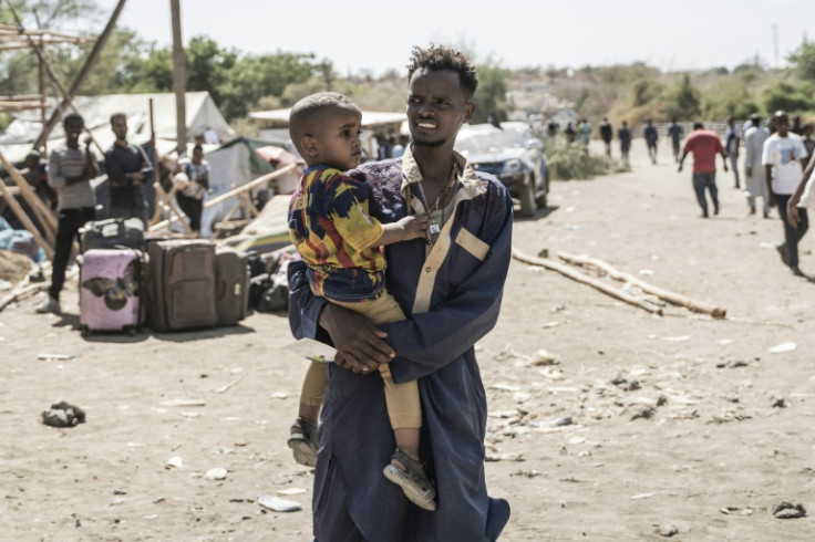 A man carries a child at the border town of Metema, the crossing point for thousands fleeing from Sudan into Ethiopia