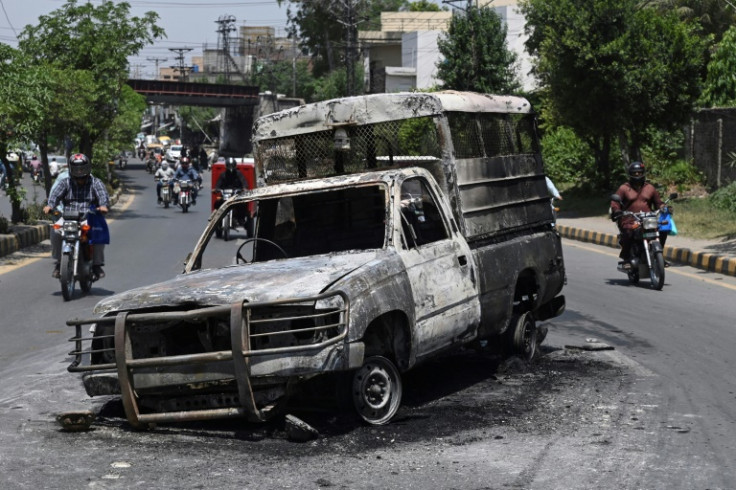 A vehicle set on fire during protests against the arrest of former prime minister Imran Khan blocks a road in Lahore