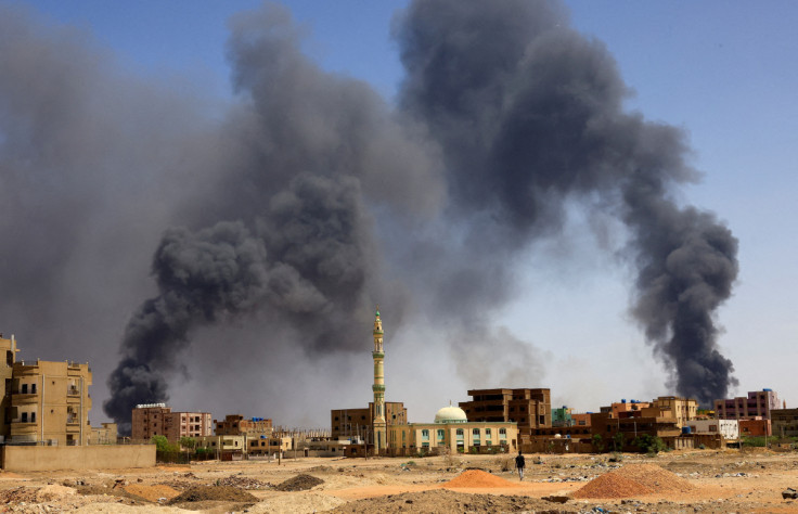Man walks while smoke rises above buildings after aerial bombardment in Khartoum North