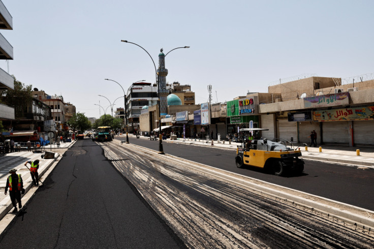 Iraqi workers lay asphalt as a Al-Karada street is paved in Baghdad