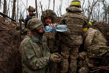 A Ukrainian soldier gives waterto a captured Russian army serviceman near the front line city of Bakhmut