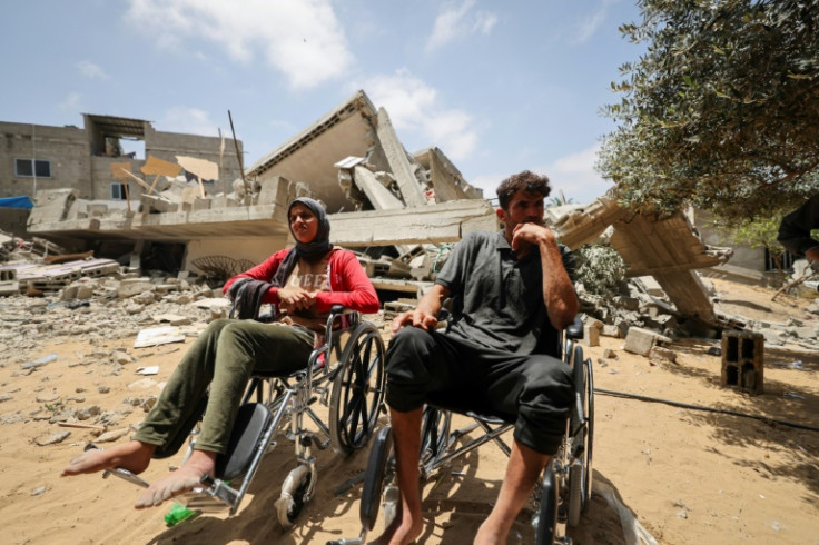 Members of the Palestinian Nabhan family sit in wheelchairs by the rubble of their home, flattened in an Israeli air strike in Beit Lahiya in the northern Gaza Strip