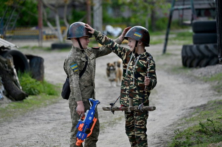 Ten-year-old Maksym Mudrak (L) and six-year-old Valentyn (R) play war near Kyiv