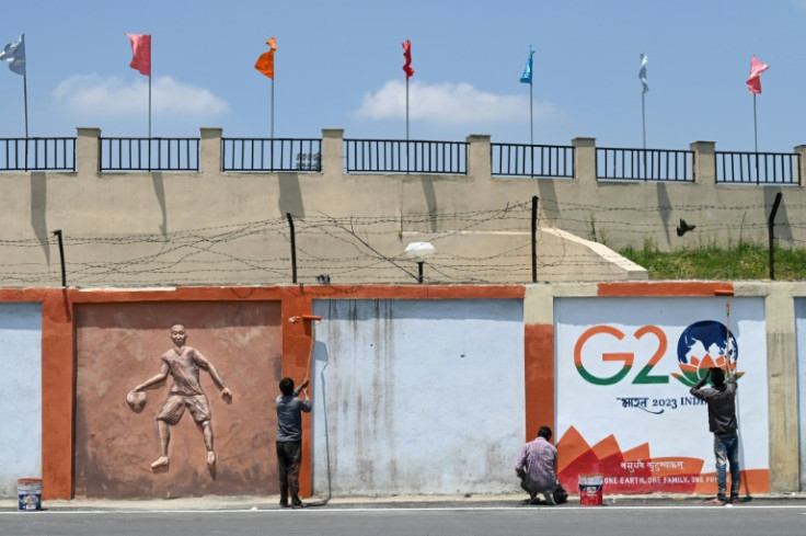 Painters give final touches to a wall mural along a street ahead of the G20 meeting in Srinagar on May 19, 2023