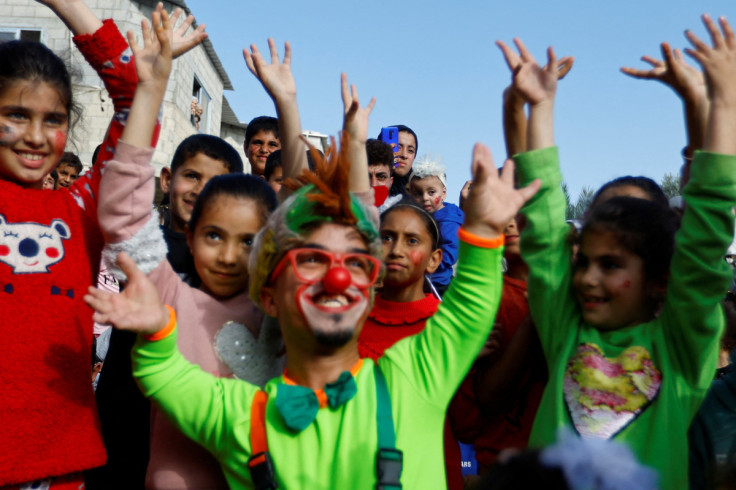 A Palestinian dressed in a clown costume entertains children in Deir al-Balah