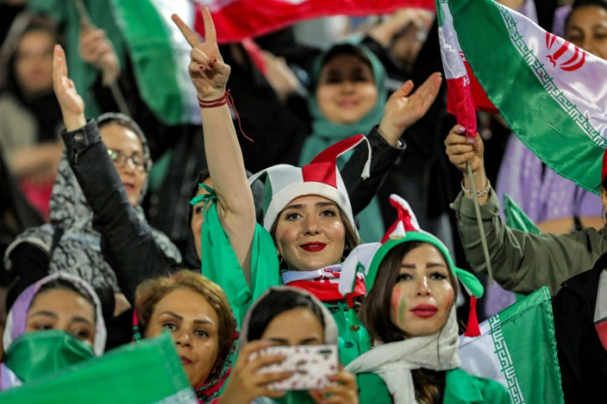 Women football fans wave national flags and cheer during a friendly match between Iran and Kenya in Tehran in March