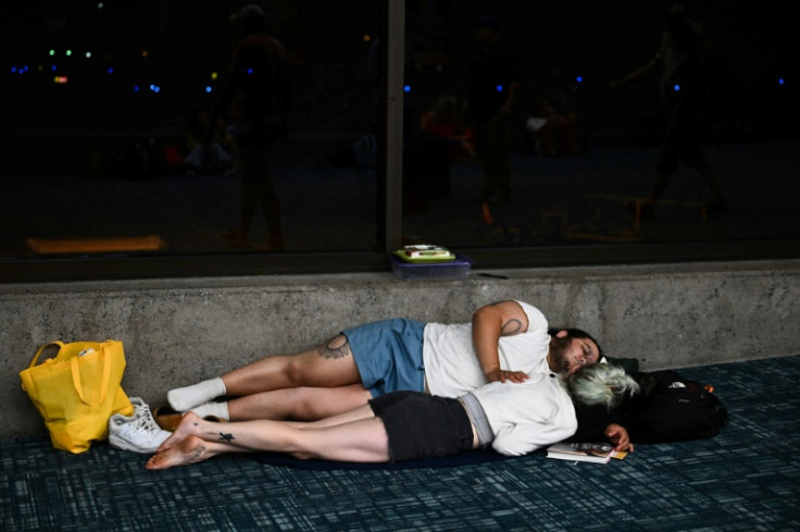 Passengers try to sleep on the floor of the Kahului Airport terminal while waiting for flights off the island of Maui, in the aftermath of wildfires that killed 36 people