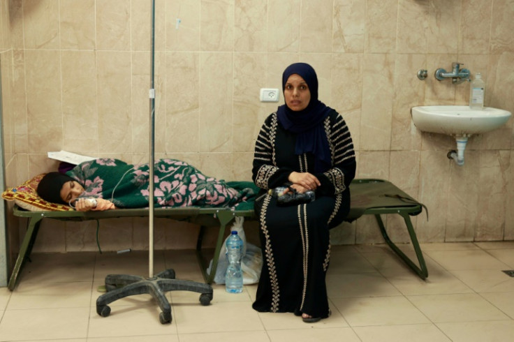 A Palestinian woman sits near an injured relative at the Al-Aqsa Martyrs Hospital in Deir El-Balah in the central Gaza Strip