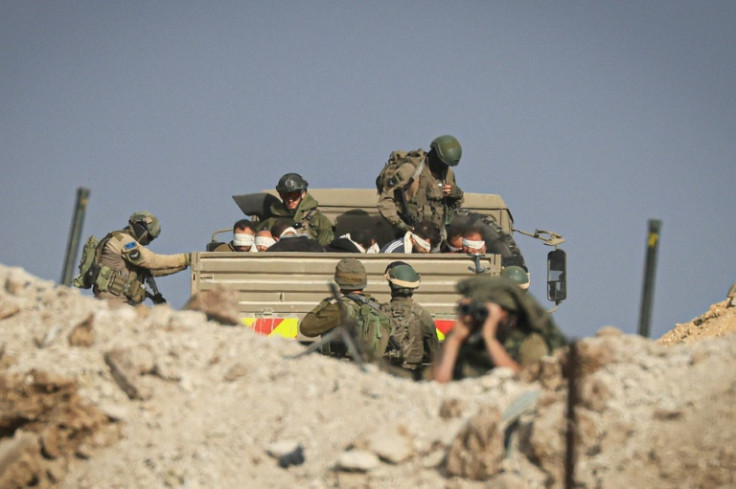 Israeli soldiers detain blindfolded Palestinian men in a military truck while Palestinians (not pictured) flee the fighting in Zeitoun district of the southern Gaza Strip