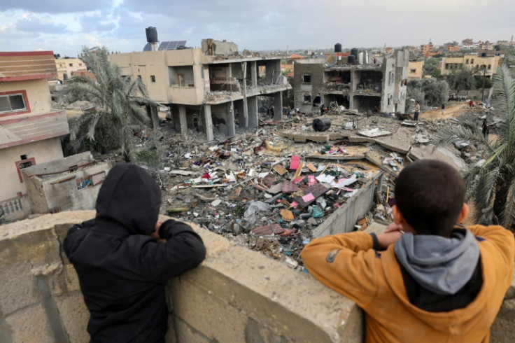 Palestinian children above the rubble of a building destroyed during Israeli strikes on Rafah, in the southern Gaza Strip