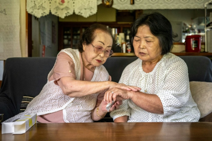 Centenarian beauty adviser Tomoko Horino (L) demonstrates products to a client in Fukushima city