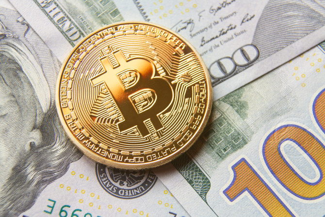 Single bitcoin with gold reflection on top of background of 