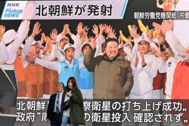 Pedestrians in Tokyo walk past a screen displaying North Korea's leader Kim Jong Un celebrating after the launch of a spy satellite on November 22, 2023