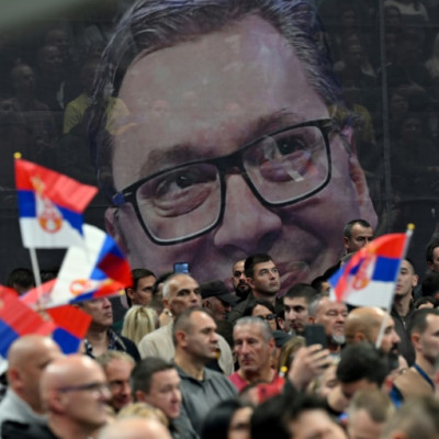 Supporters of the Serbian Progressive Party wave flags in front of a giant banner bearing a picture of Serbian President  Aleksandar Vucic during a political rally