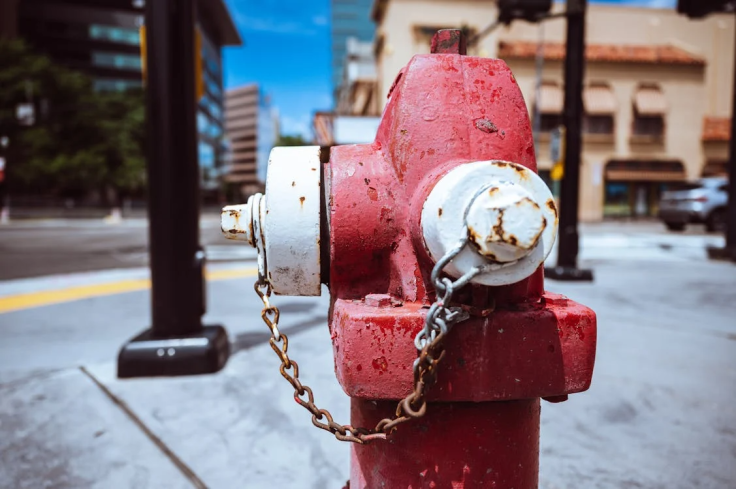 Metal fire hydrant on city street against blue sky. Representational.