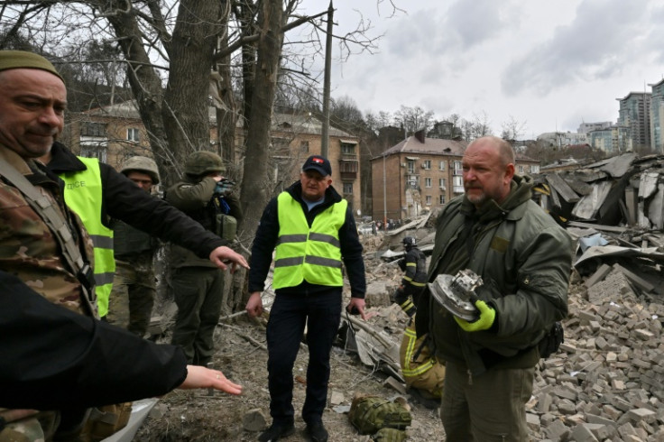 Ukrainian law enforcement officers examine fragments of a rocket at the site of a missile attack in Kyiv