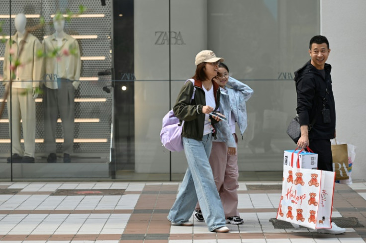 A man carries shopping bags as he walks with a woman and child in a Beijing shopping district