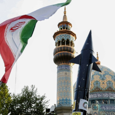 Iranians lift up a flag and the mock up of a missile during a celebration following Iran's missiles and drones attack on Israel, on April 15 2024, at Palestine square in central Tehran