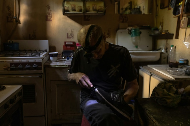 Oleksandr, 67, repairs shoes in his kitchen during an electricity blackout