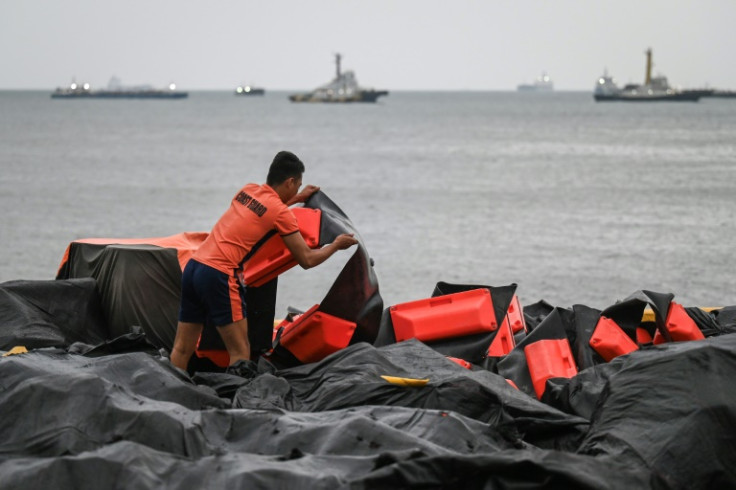 A coast guard staffer arranges an oil spill containment boom to be use3d in Manila Bay