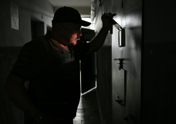 A Ukrainian officer looks into a cell where Russian POWs are being held