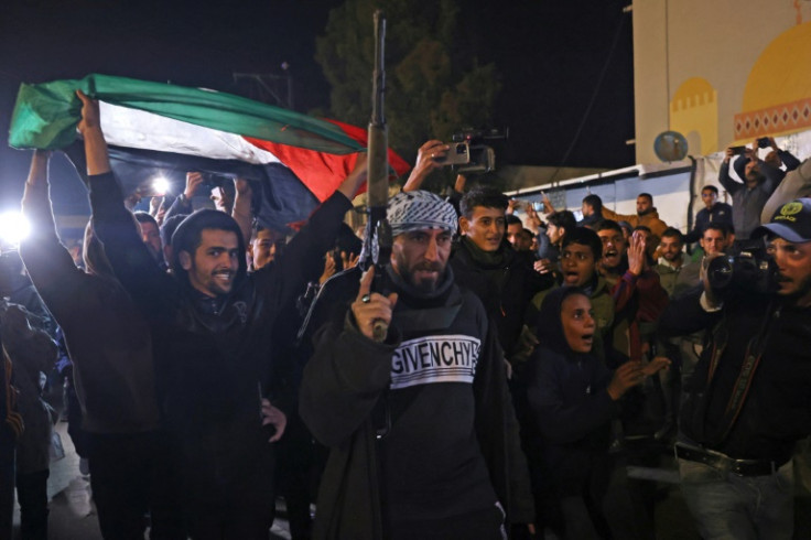 People celebrate while watching a television along a street in Khan Yunis in southern Gaza as news spread of a ceasefire deal