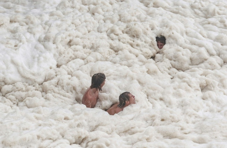 Young men play in sea foam created by record-breaking waves as the outer fringe of Tropical Cyclone Alfred started whipping eastern Australia, in Coolangatta on March 6, 2025. Tropical Cyclone Alfred was 285 kilometres (180 miles) east of busy Brisbane ci