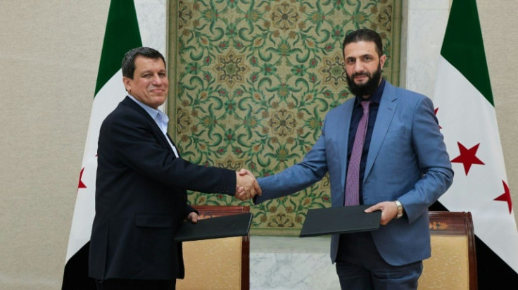 Syrian interim president Ahmed al-Sharaa (R) shakes hands with Syrian Democratic Forces (SDF) head Mazloum Abdi after signing an agreement in Damascus
